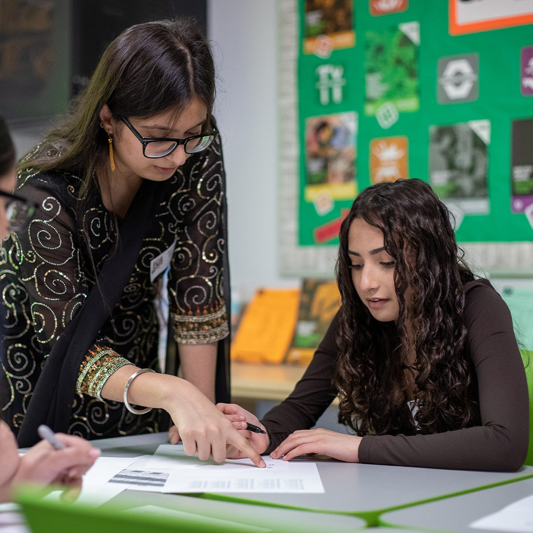 An event leader showing a student some work on a sheet.