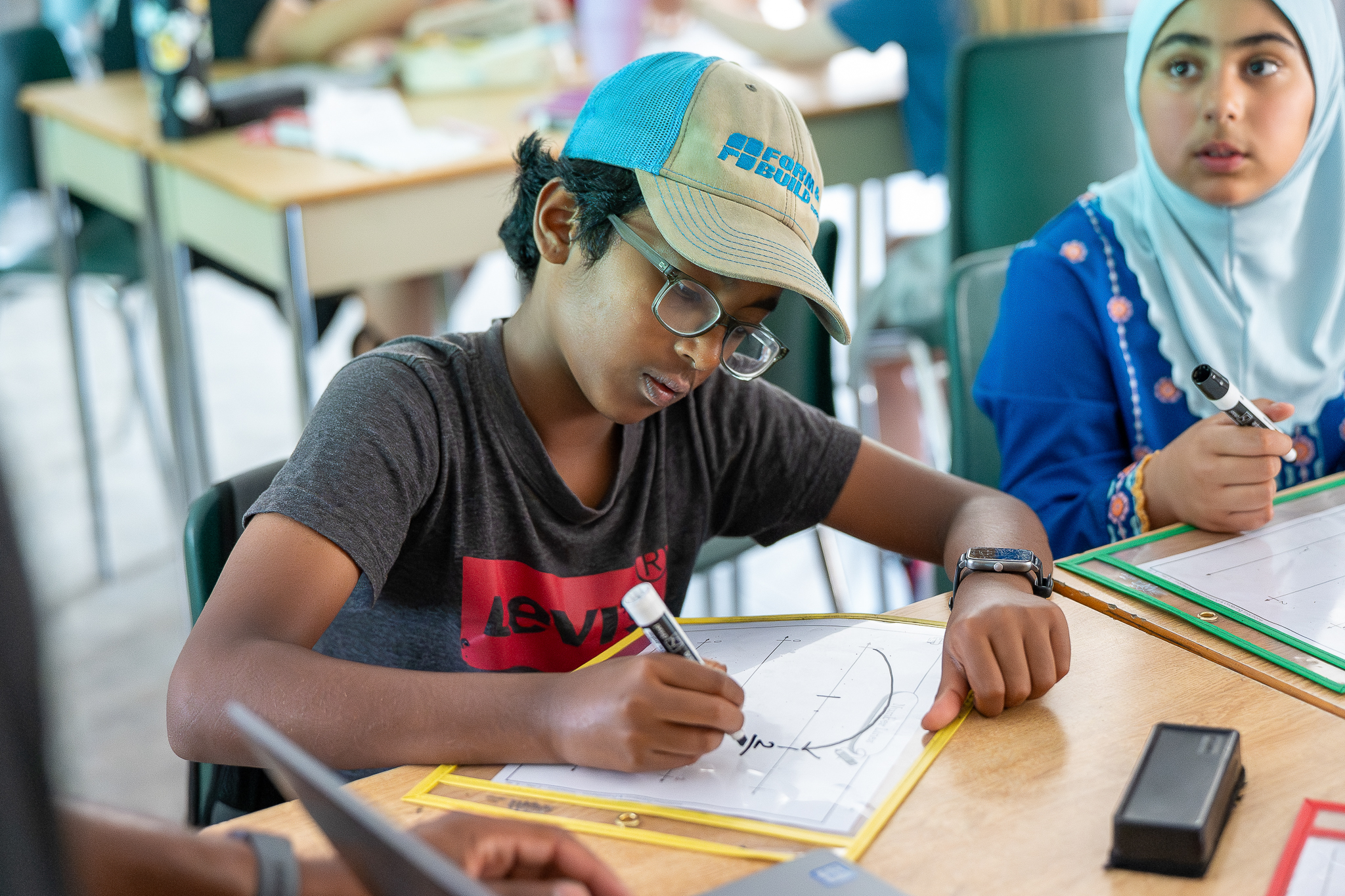 Students working on math with markers sitting at a desk