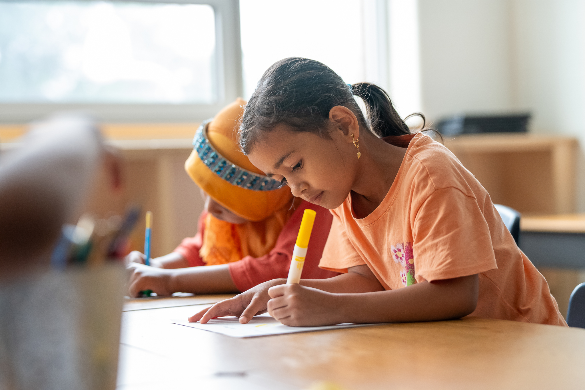 Elementary students engaged in writing activity with markers