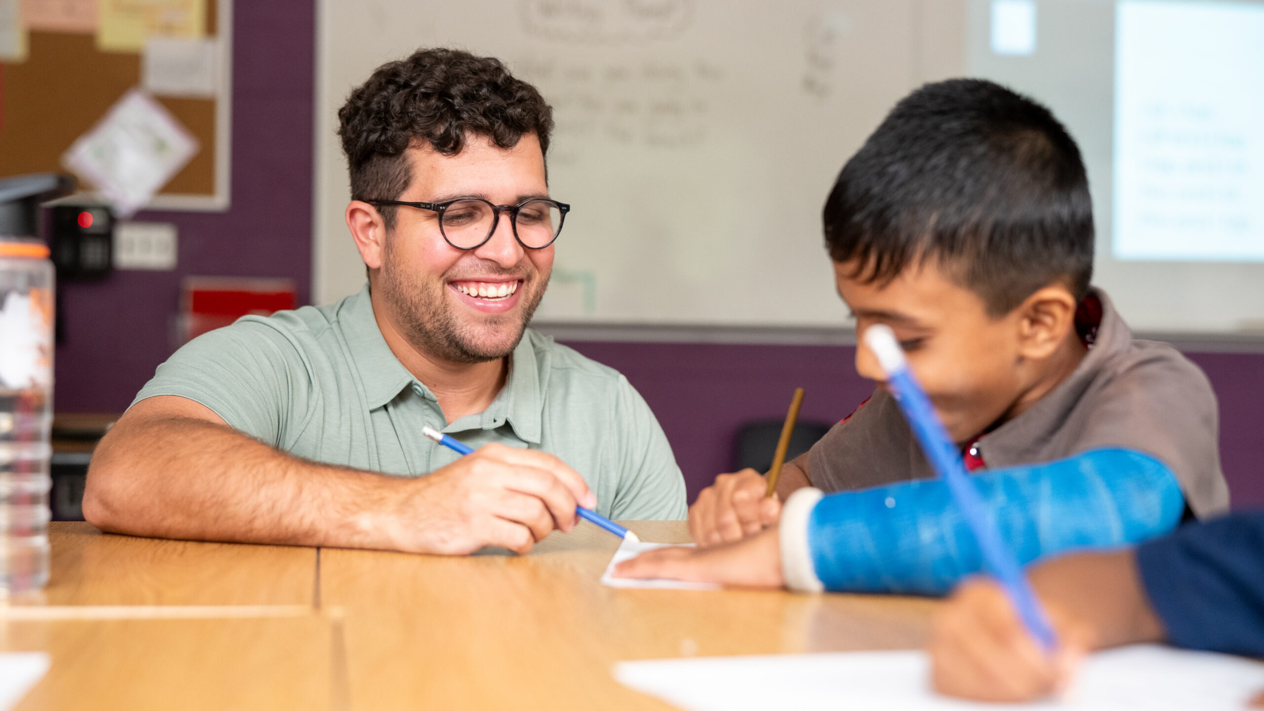 Educator smiling working at desk with enthusiastic student