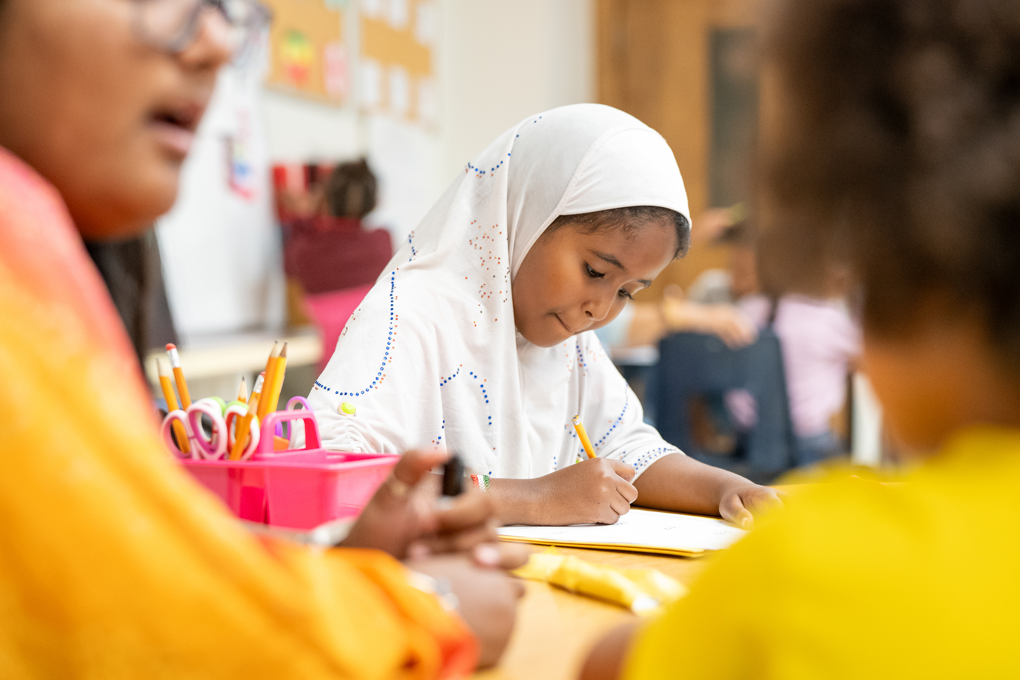 Student engaged in classroom work with educator and other students at the table
