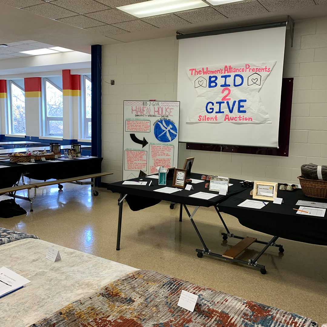 A look at the silent auction area, with the items displayed on tables with sheets of paper for people to bid with. 