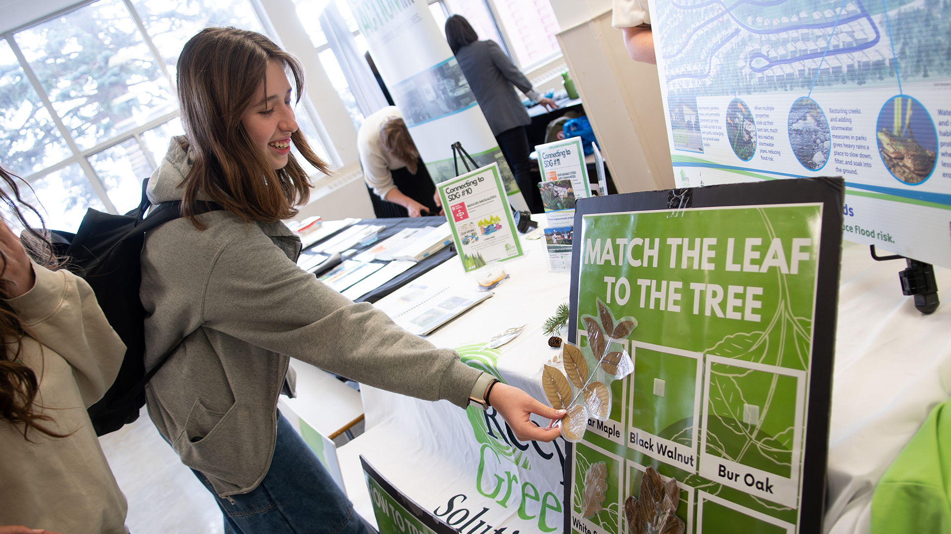 Student puts a leaf on a board that reads "match the leaf to the tree"