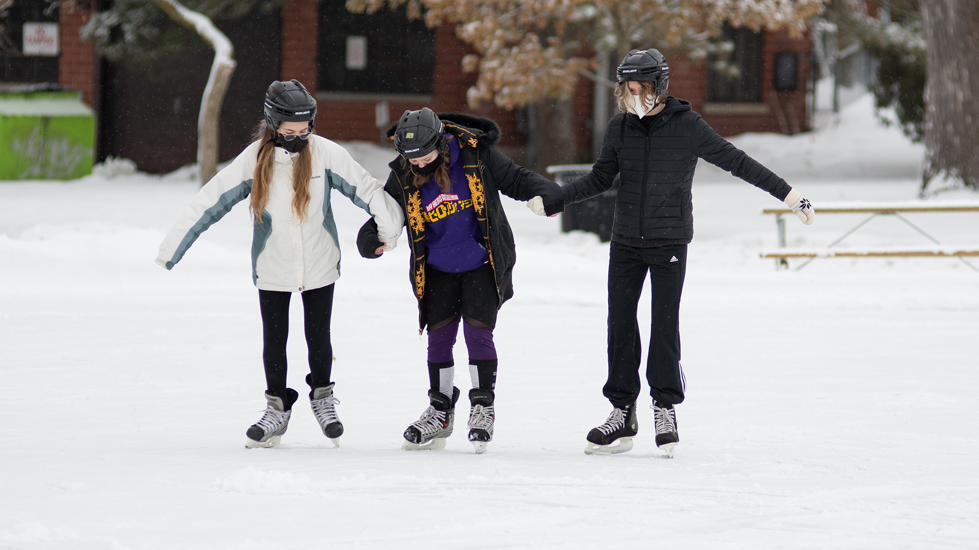 Photo of three students skating together, to support the one in the middle