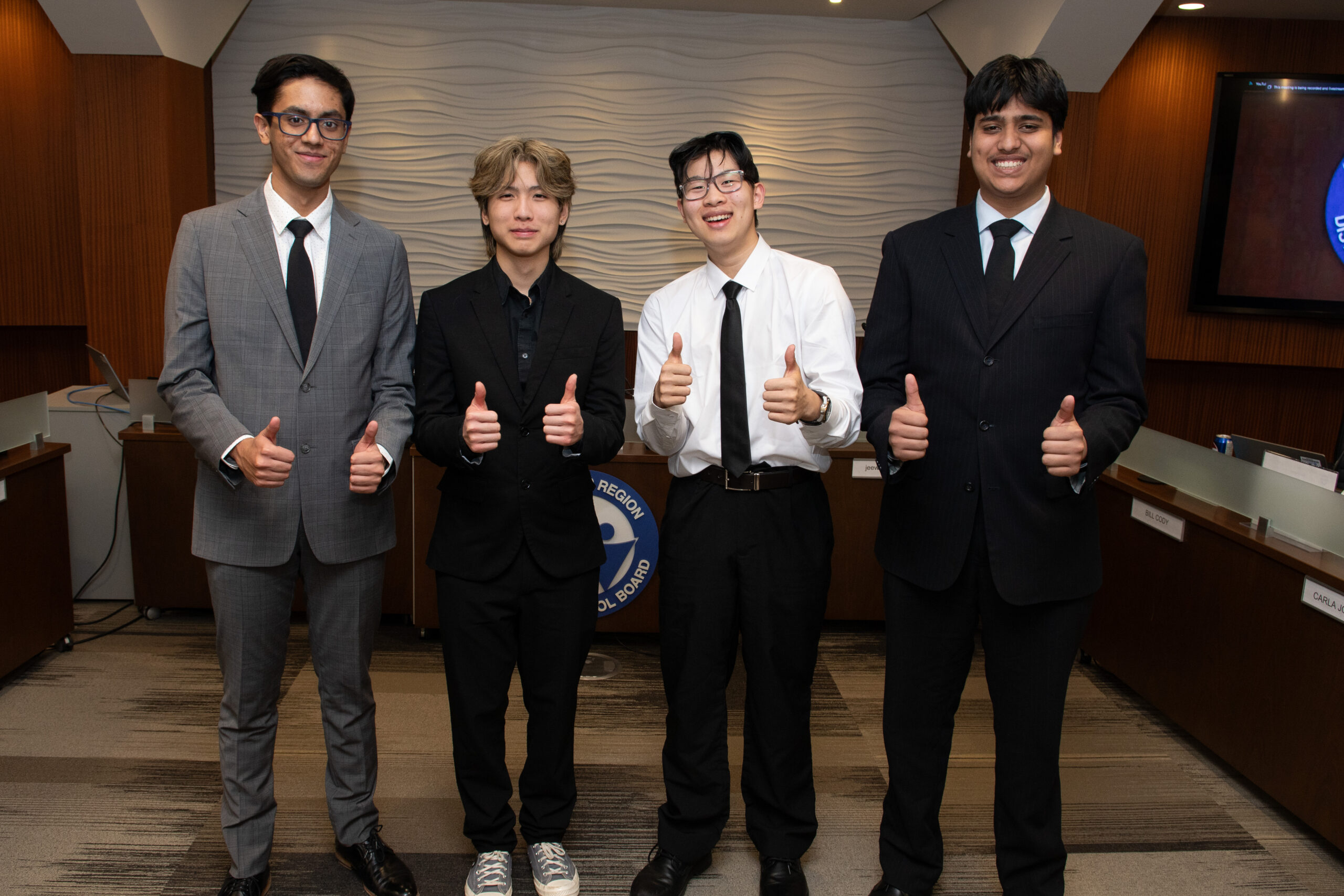Incoming Student Trustees Devansh and Feiyang stand with current Student Trustees Casper and Abdullah, showing a thumbs up.