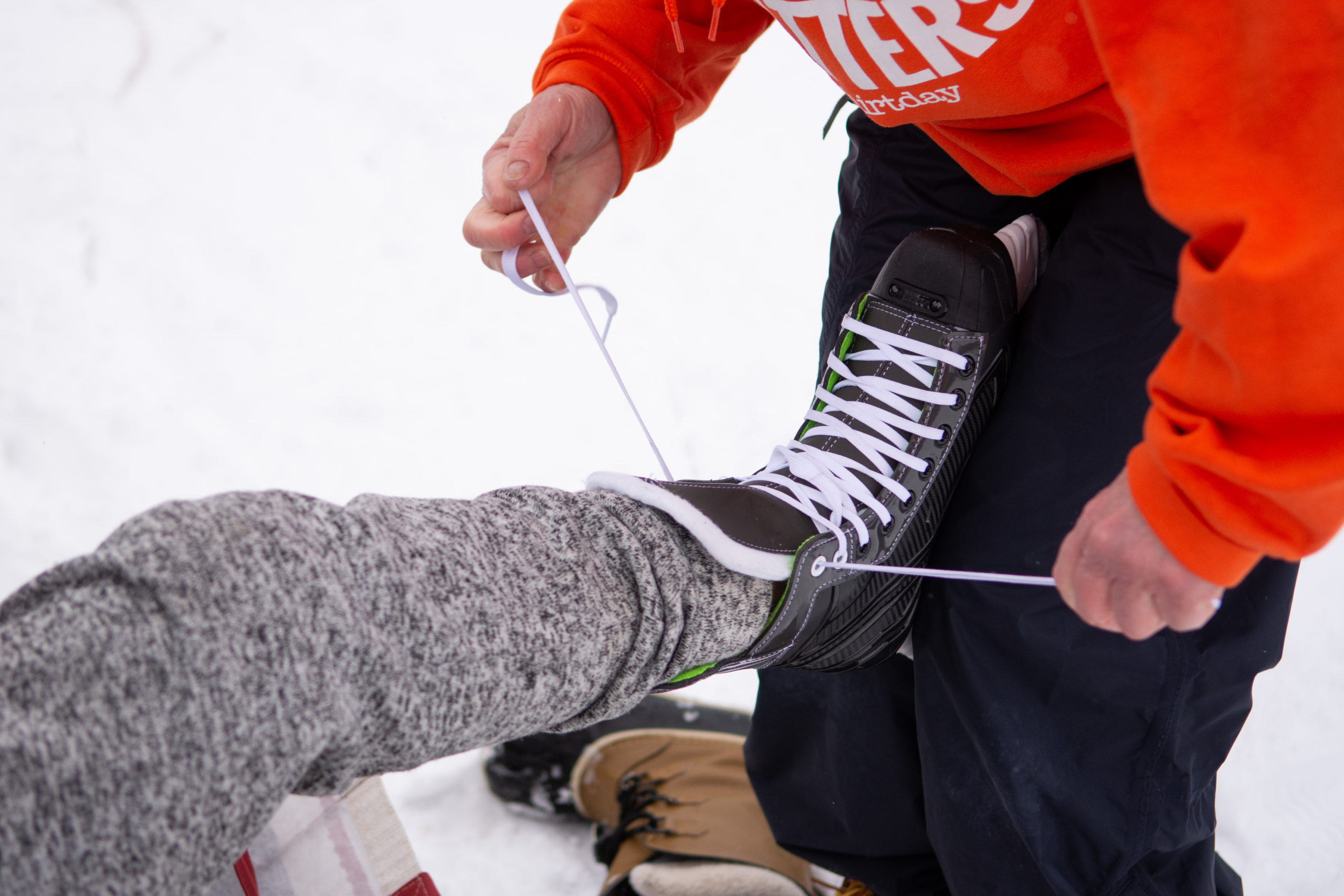 A student's skates are laced up by a staff member.