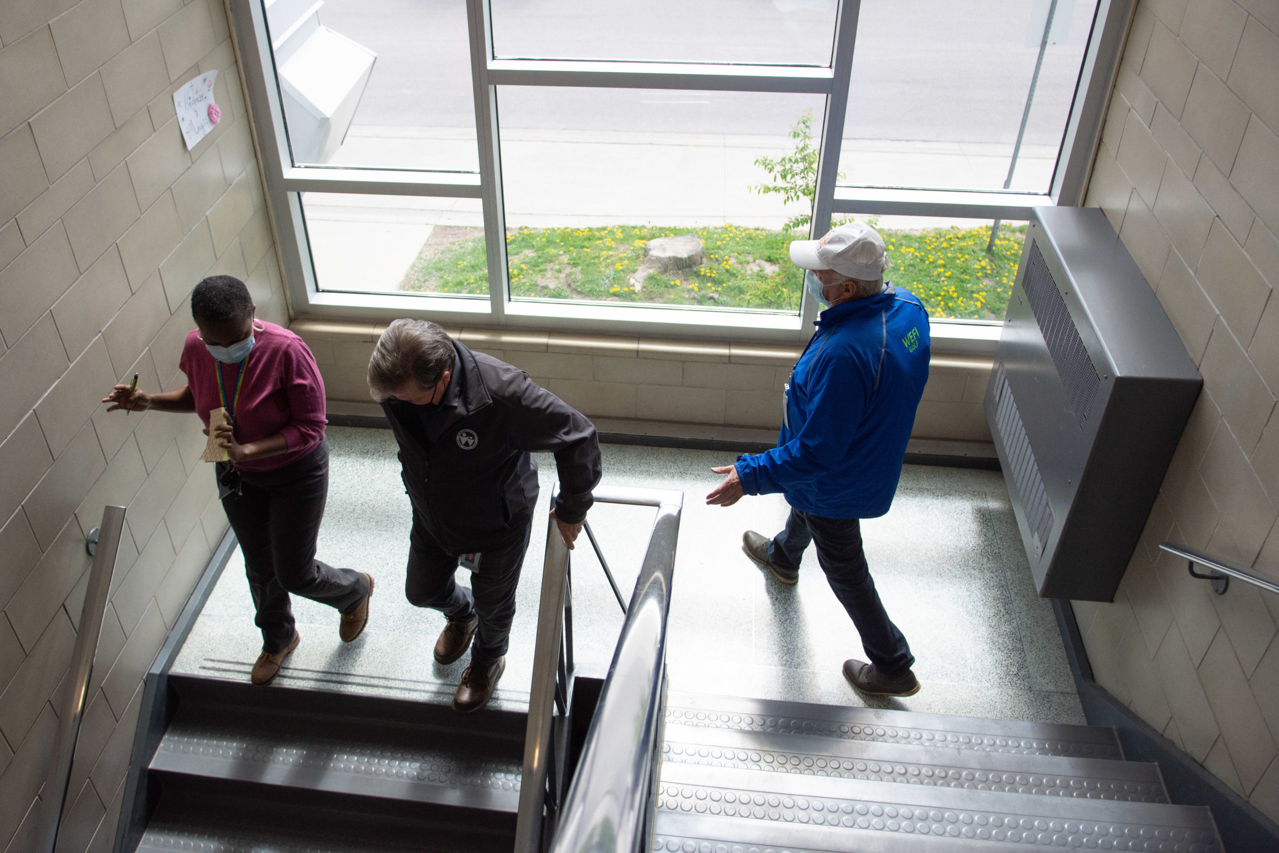Three people walk down a large staircase at King Edward PS.