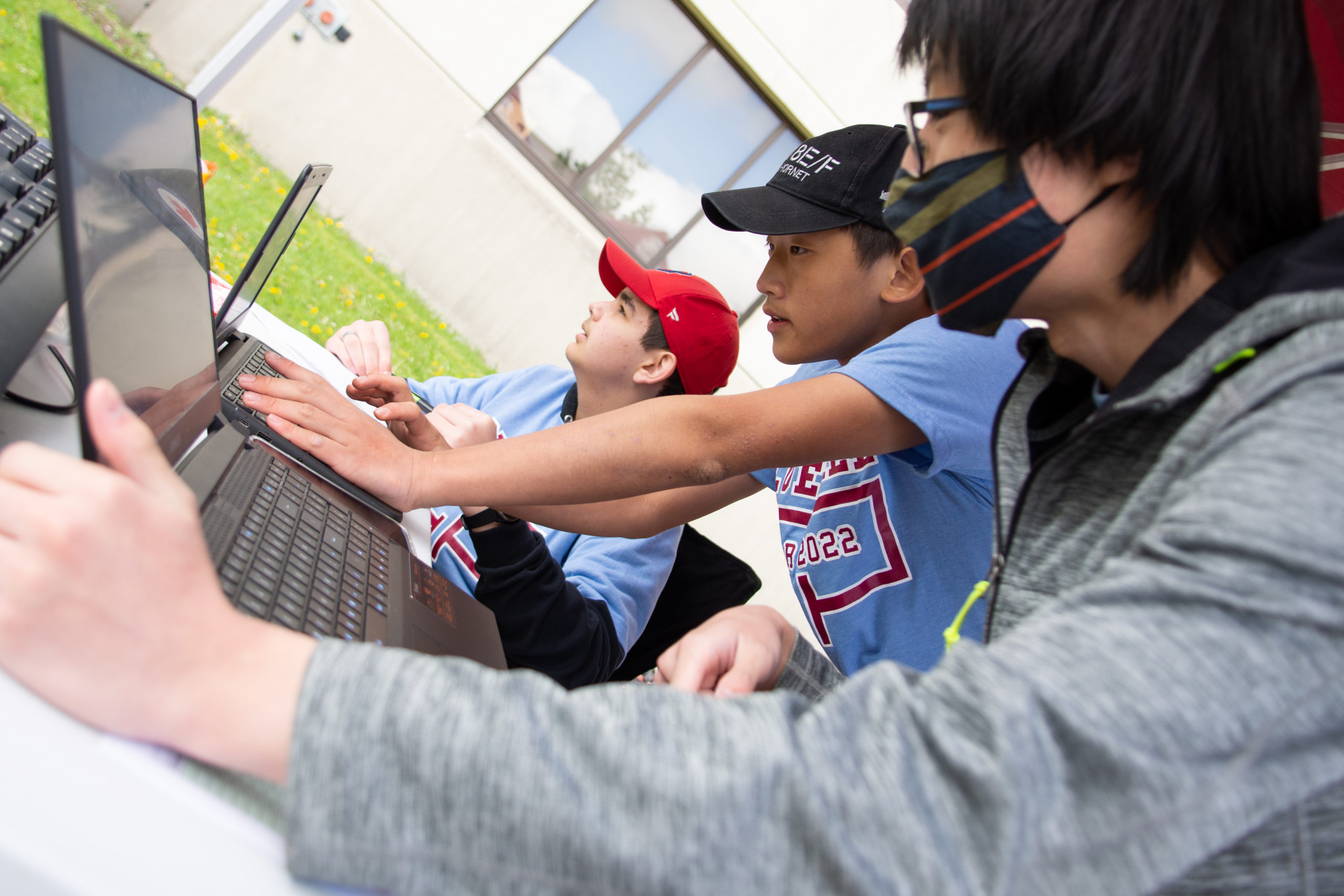 Three students each carefully studying data on their laptops during the race. 