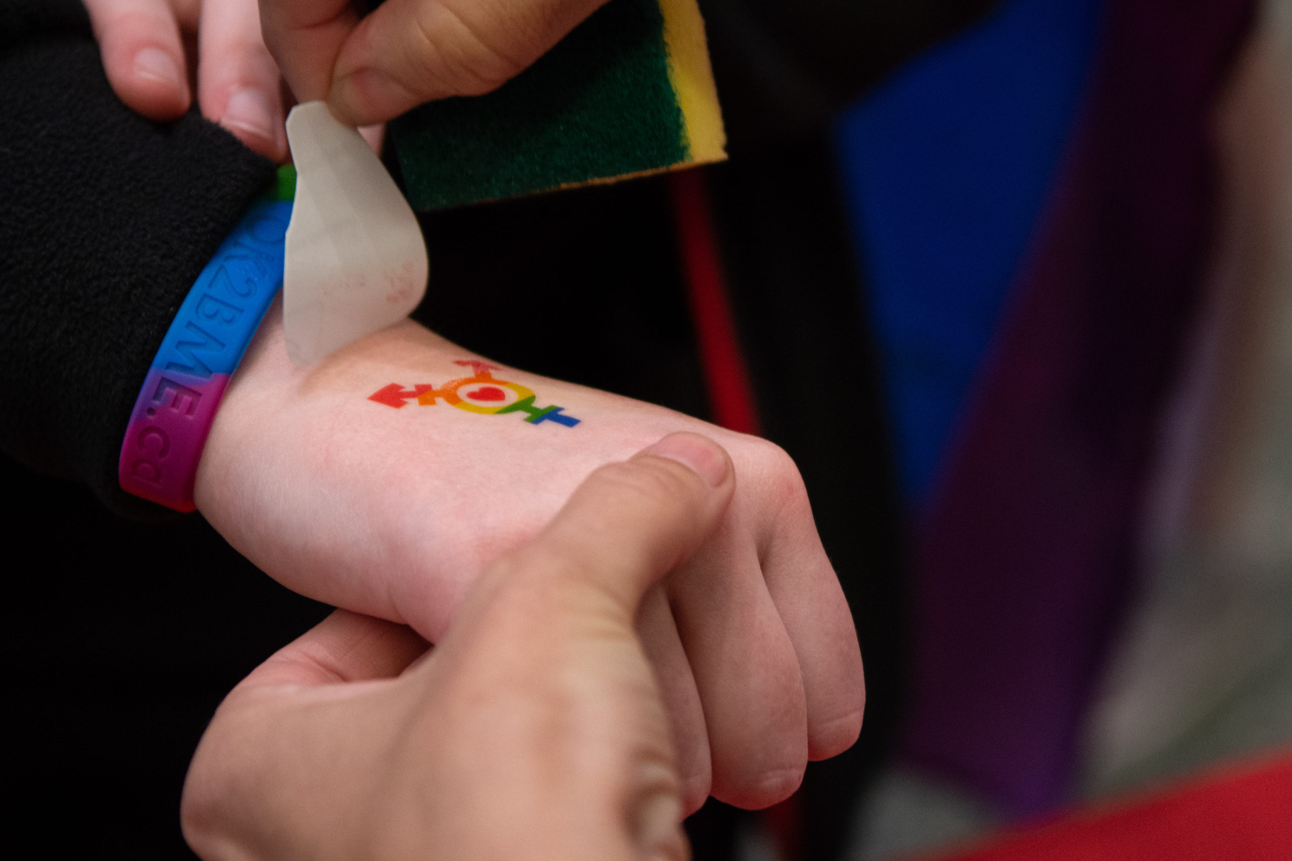 A temporary Pride-themed tattoo is applied to a hand.