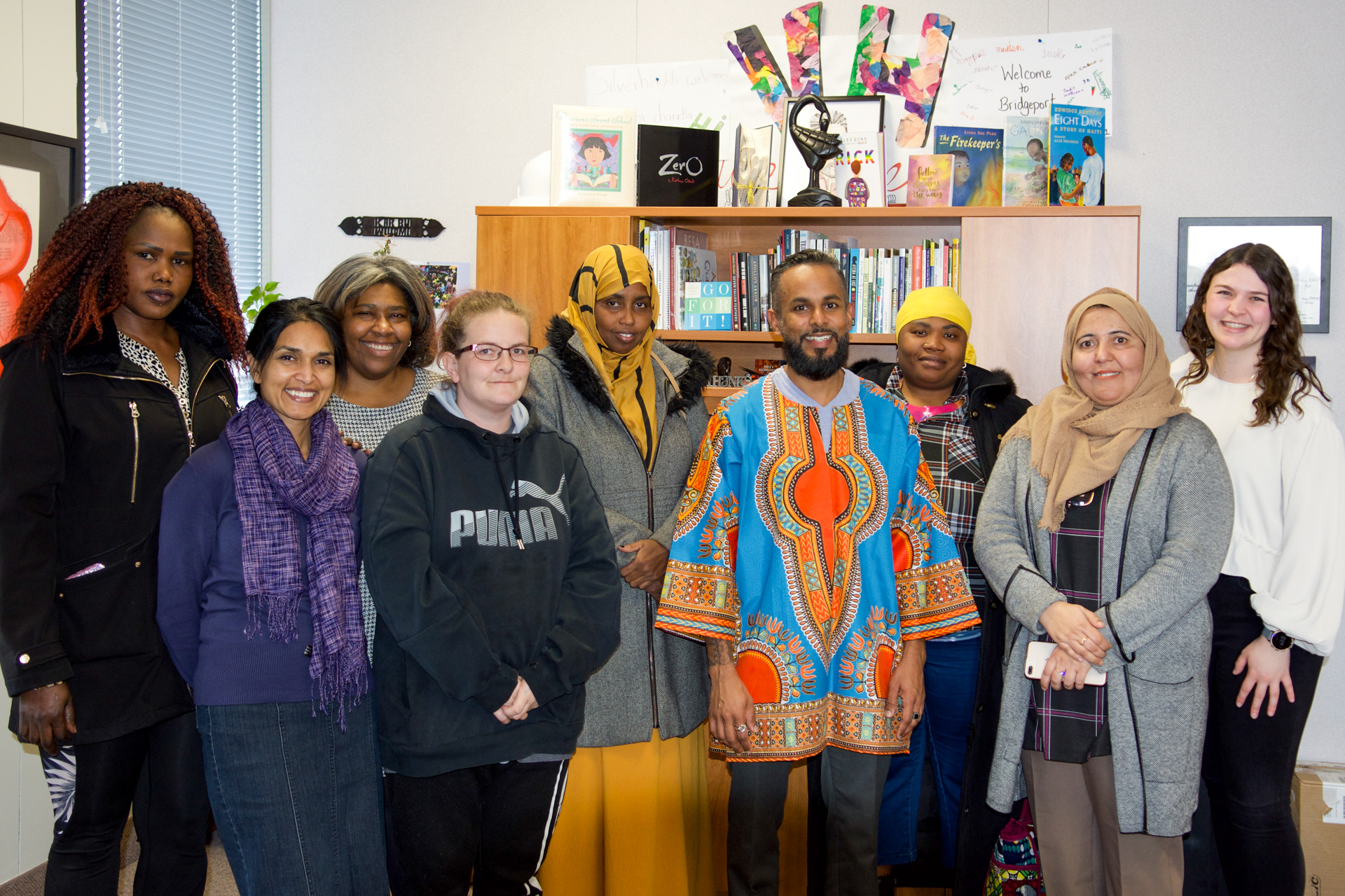 jeewan chanicka, director of education, stands with mothers from Adventure 4 Change. jeewan is wearing a brightly coloured blue and orange African Dashiki.