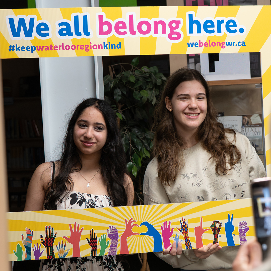 Student standing with a We All Belong Here selfie prompt